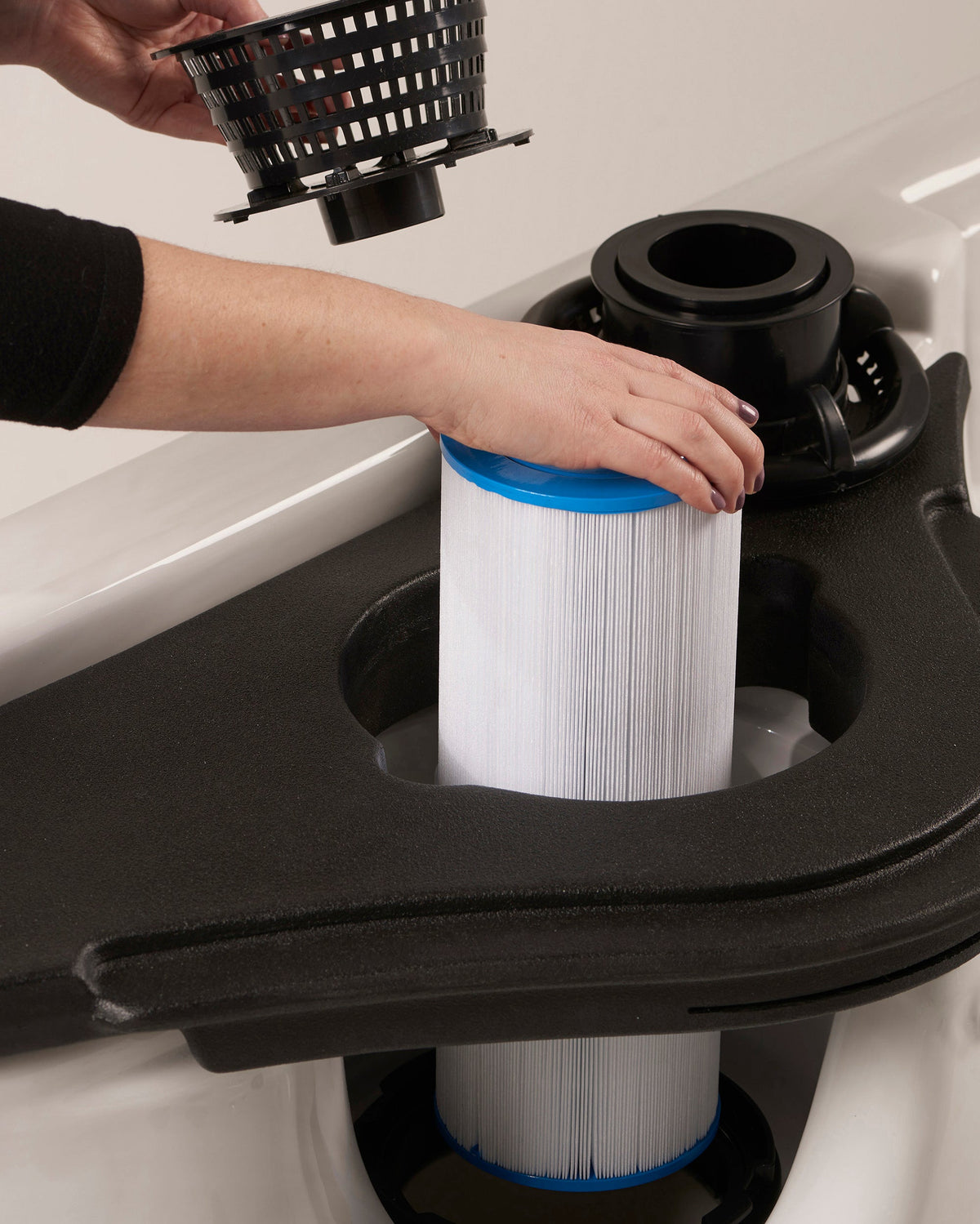 Person replacing a filter in a hot tub with a close-up view of the filter and hands.