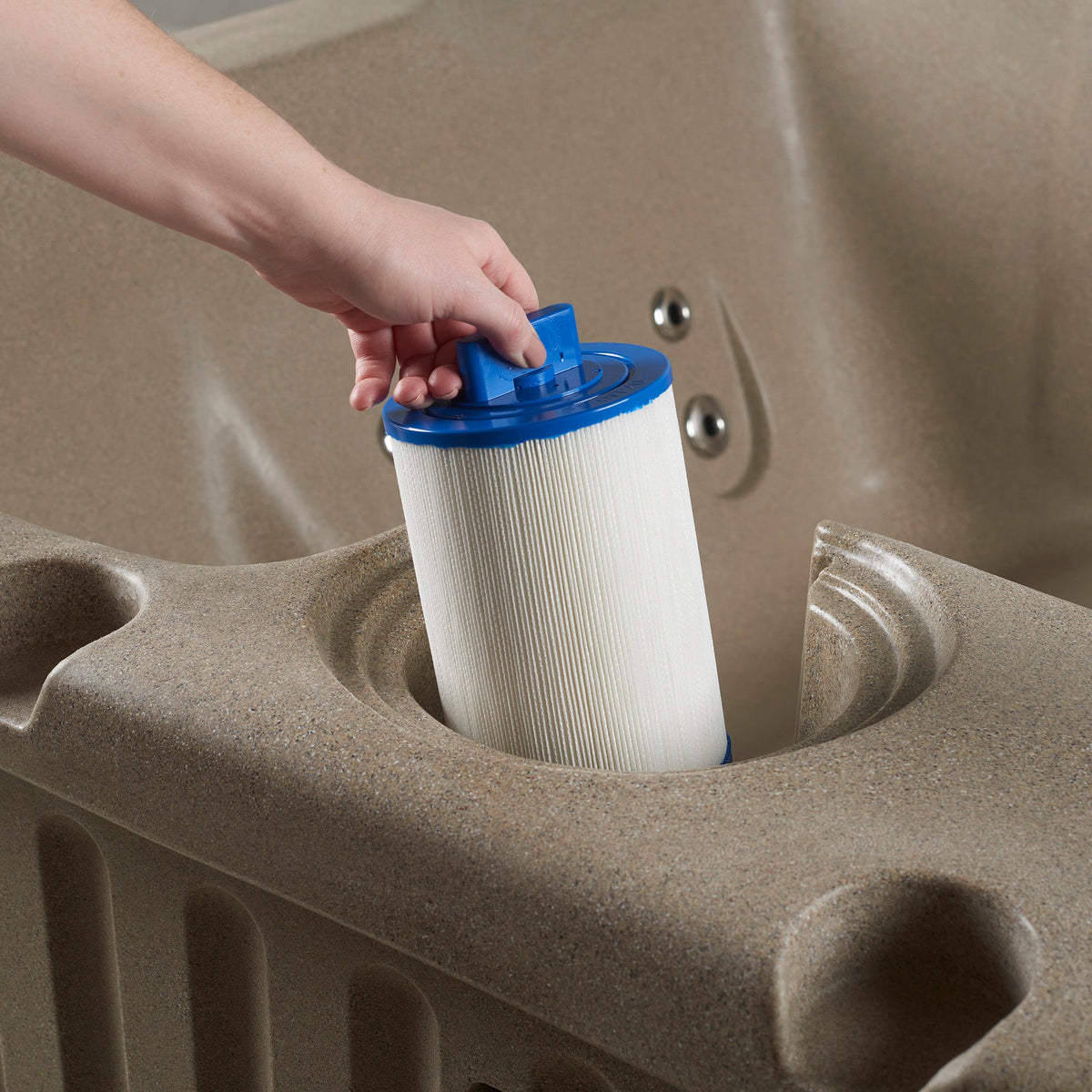 hand putting spa filter into tan resin hot tub