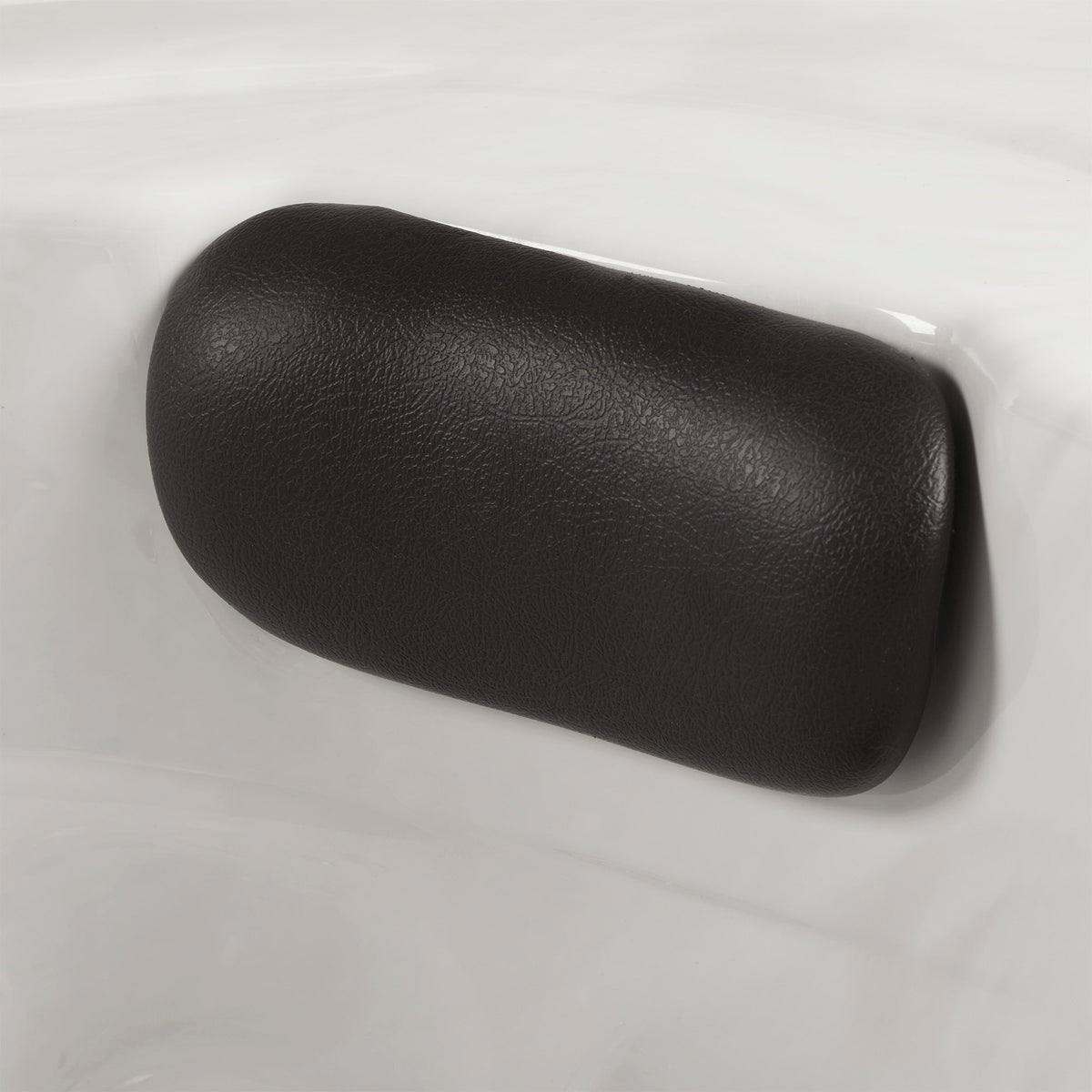 A black spa pillow with a textured leather-like finish, shown on a white acrylic spa shell