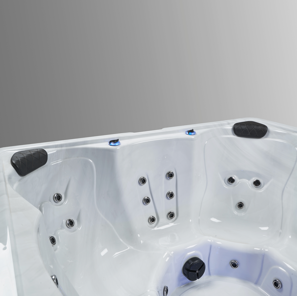 A close-up studio shot of a white hot tub interior showing the molded shell, multiple black jet nozzles, and black accents against a neutral gray background.