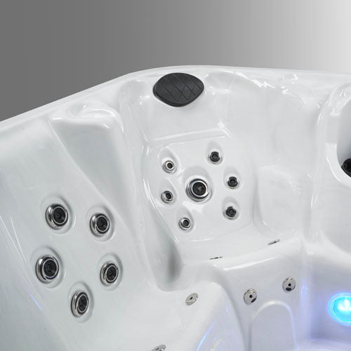 Close-up of a white hot tub interior showing multiple jet nozzles, a black non-slip pad, and blue water lighting.