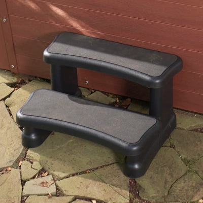 Two-step outdoor steps with textured non-slip grips, shown on a stone patio in front of a brown wooden hot tub.