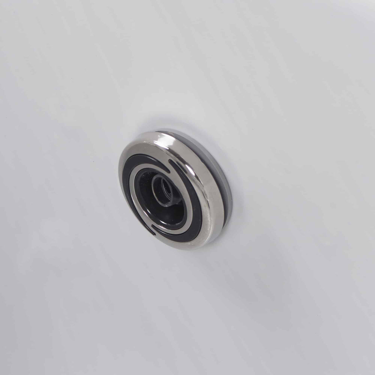 Stainless steel spa jet on white spa shell