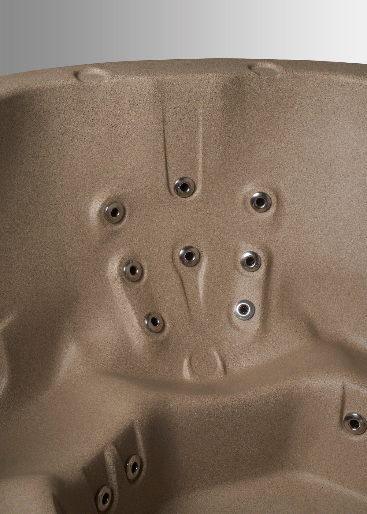 Close-up of a beige hot tub or spa interior showing molded seating contours and multiple circular jet openings. #color_cobblestone