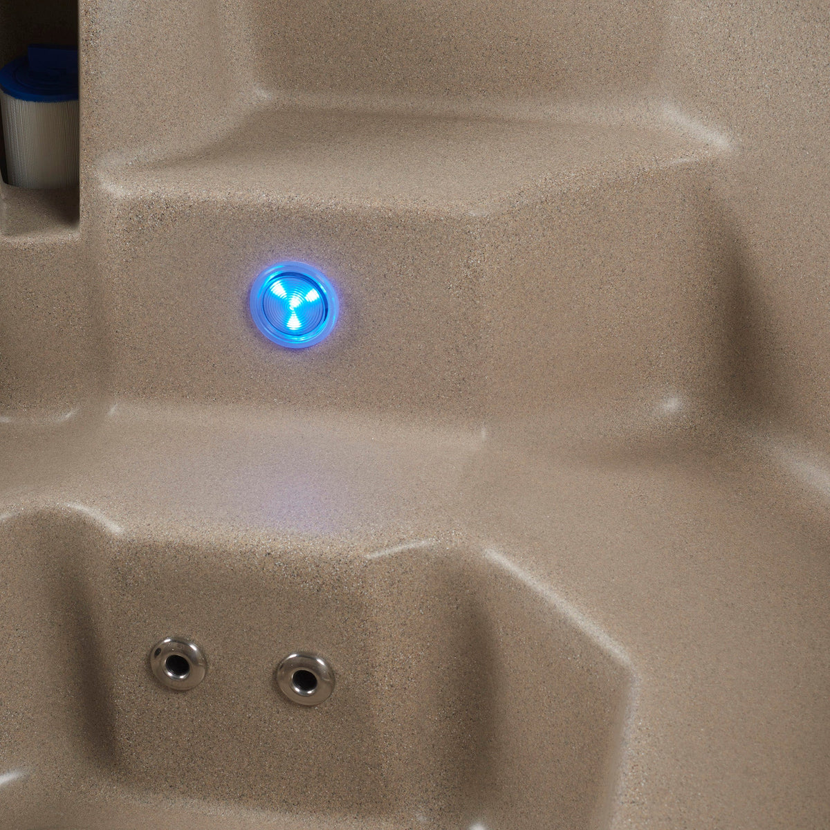 Close-up of a beige textured spa or hot tub seat with a glowing blue LED light and two silver jet nozzles visible. #color_cobblestone