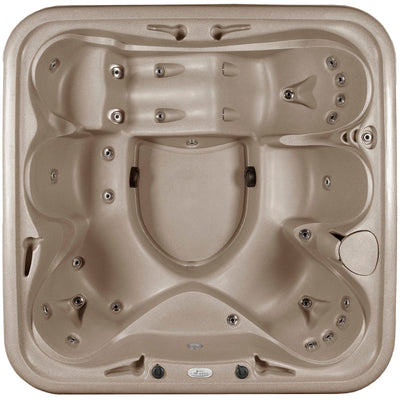 Top-down view of a spa hot tub in a warm taupe/beige color, featuring multiple seating zones, jet nozzles, and control buttons.