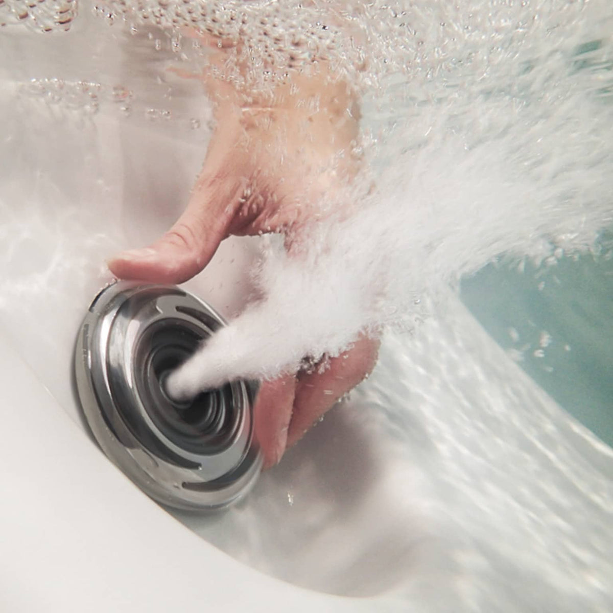Hand turning a spa jet in a hot tub filled with water and bubbles
