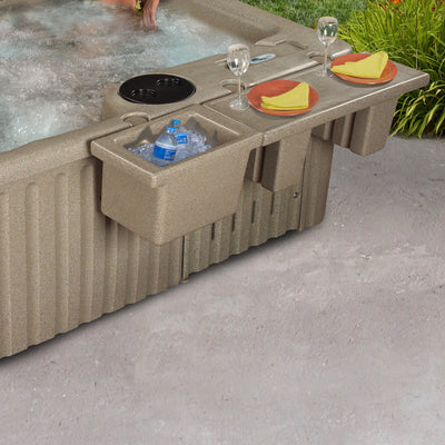 A beige hot tub with an integrated side bar and ice bucket, shown outdoors on a concrete patio with food and drink accessories placed on the bar.