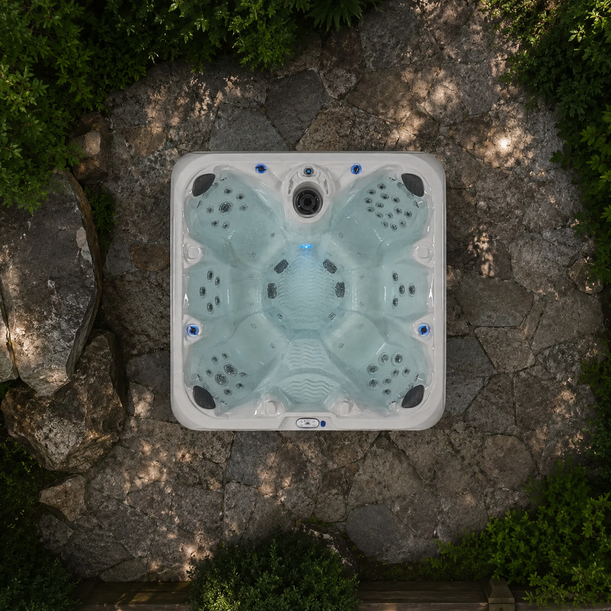 Hot tub on a stone patio surrounded by greenery