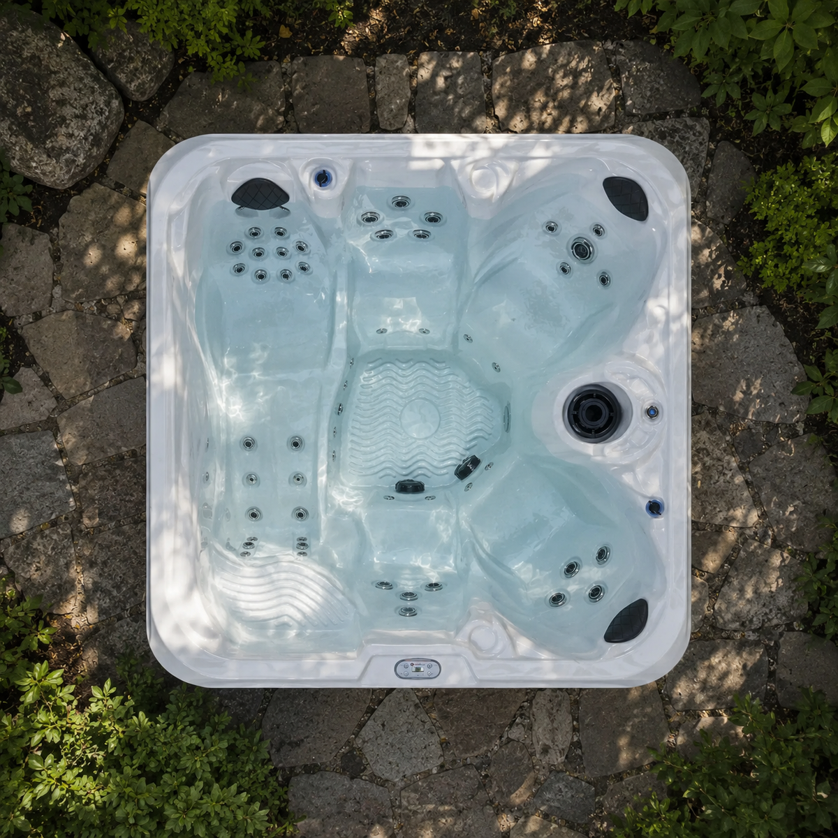 Top view of a hot tub on a stone patio with greenery around