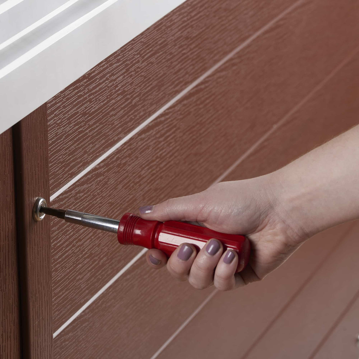 Hand using a red screwdriver on the panel of a hot tub