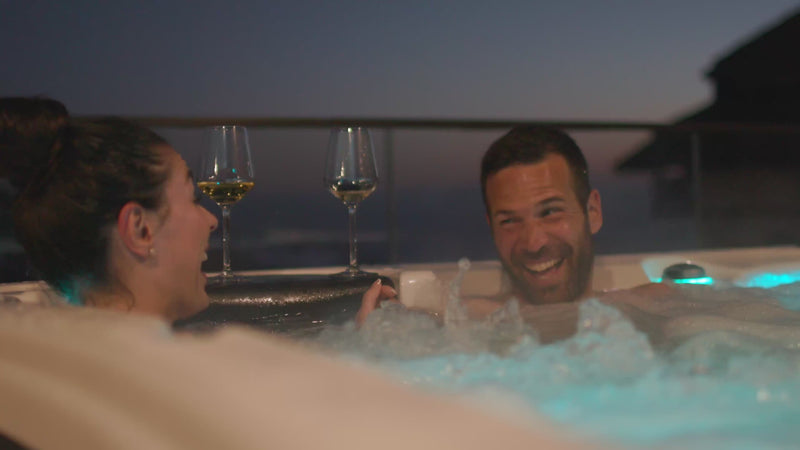 couple with champagne glasses in hot tub at night laughing and smiling