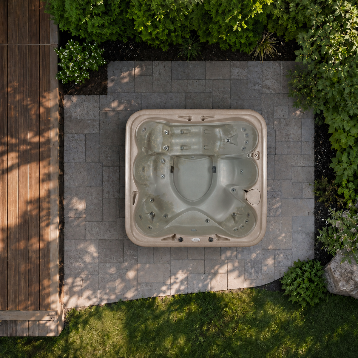 Top-down view of a hot tub surrounded by greenery and a paved area.