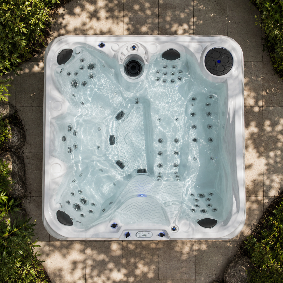 Top-down view of a hot tub with water and bubbles, surrounded by greenery.
